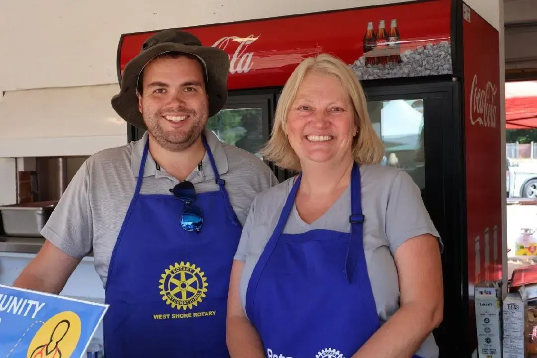 Two members smiling in Rotary aprons at a fundraiser