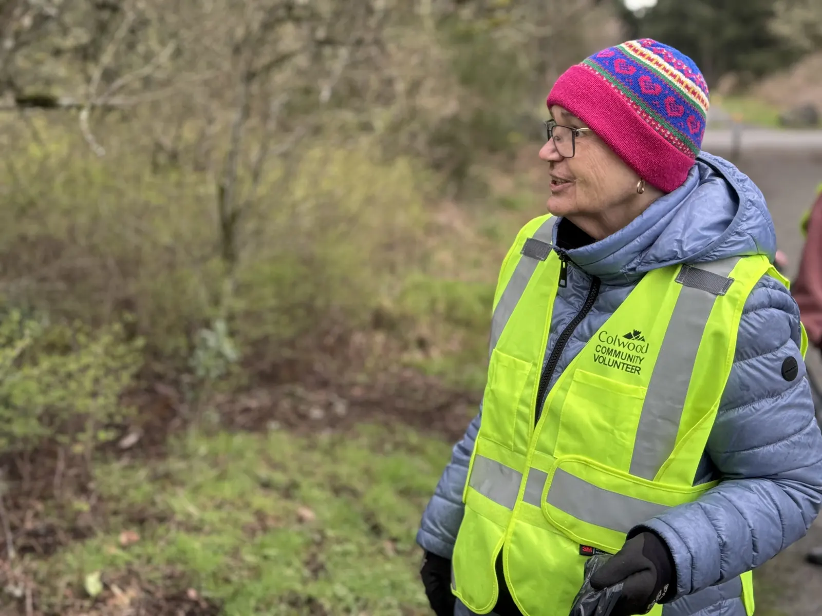 A member in a colourful toque and safety vest at a trail cleanup
